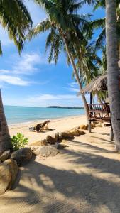 a bench on a beach with palm trees and the ocean at Castaway Beach Bungalows in Srithanu