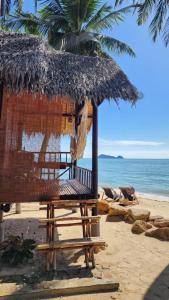 a straw umbrella and a chair on a beach at Castaway Beach Bungalows in Srithanu
