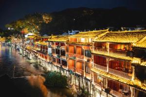 a row of buildings next to a river at night at Bian Cheng Xing Zi Inn in Fenghuang County