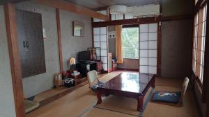 un soggiorno con un tavolo di legno e una stanza con una finestra di 三介荘 a Izunokuni