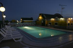 a swimming pool at night with chairs and a building at Residence Cristoforo Colombo in Caorle