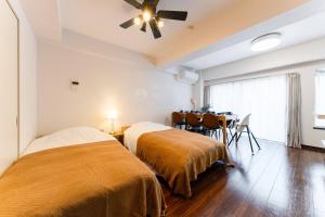 Dos camas en una habitación con mesa de comedor. en Villa mitamura 303 VM33, en Tokio