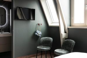a room with three chairs and a tv on a wall at THE FRITZ Hotel Amsterdam in Amsterdam