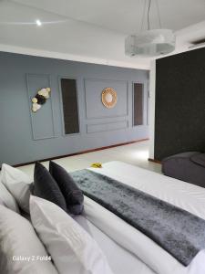 a bedroom with a large bed with white sheets and pillows at Sunshine Inn in Gaborone