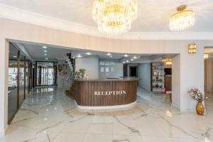 a hotel lobby with a reception desk and chandeliers at Safari Otel in Antalya