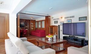 a living room with a large television and white furniture at Limassol Beachfront Holiday Villa in Limassol