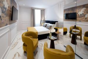 a hotel room with a bed and chairs at Le Cinque Lampade Florence Suites in Florence