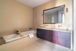 a bathroom with a tub and a sink and a mirror at Frank Porter - Diamond, Tiara Residences in Dubai