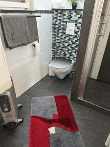 a bathroom with a toilet and a red rug at Holzhaus Leverkusen in Leverkusen +1 photo