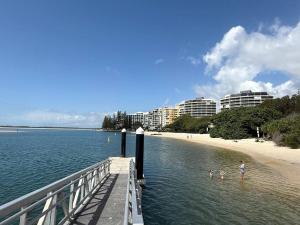 a person standing in the water next to a pier at Gemini Resort, 2bedroom Unit19 and carpark Golden Beach, Caloundra in Golden Beach