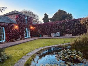 a house covered in ivy with a pond in the yard at The Old Coach House at Stewton in Louth