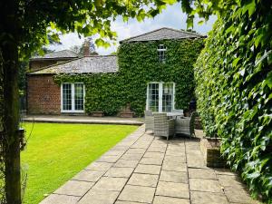 a garden with chairs and a house with ivy at The Old Coach House at Stewton in Louth