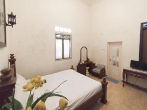 a bedroom with a bed and a table and a window at Intayu Homestay RedPartner in Gubukklakah