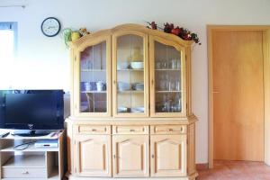 une grande armoire en bois dans une pièce avec une télévision dans l'établissement Ferienwohnung Nr 1, neben einem Bauernhof, Roßhaupten, Allgäu, à Roßhaupten