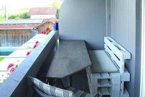 d'un balcon avec un banc et une table. dans l'établissement Ferienwohnung Nr 1, neben einem Bauernhof, Roßhaupten, Allgäu, à Roßhaupten