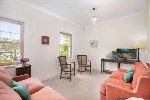 a living room with orange furniture and a fish tank at Merri Cottage in Bowral