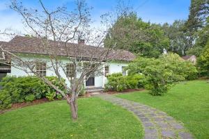 a white house with a tree in the yard at Merri Cottage in Bowral