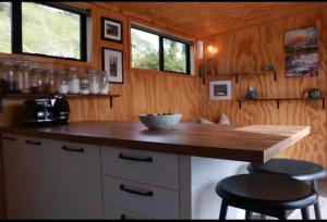 a kitchen with a wooden counter and two stools at White Pine Bush Cabins in Otangihaku