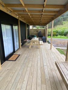 a wooden deck with a table and chairs on it at Te Mata Retreat in Tapu