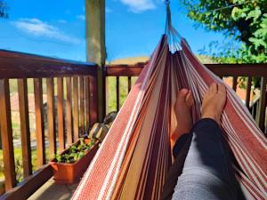 a person laying in a hammock on a porch at Casa do Rio, Natureza - Nova Gestão in Melgaço