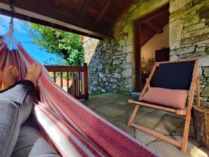 a person laying in a hammock on a porch at Casa do Rio, Natureza - Nova Gestão in Melgaço