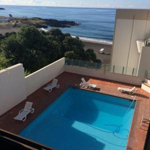 una piscina en la parte superior de un edificio con vistas al océano en Populo Beach Apartment, en São Roque