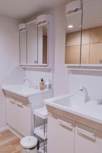 a white bathroom with two sinks and a toilet at Guesthouse TOMARITOMARO in Shikineshima +31 photos