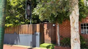 a fence with a tree in front of a building at Shiralee Hostel -note - Valid passport required to check in in Perth