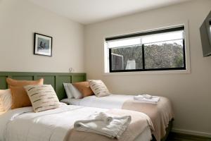 two beds in a room with a window at Rocky Valley Luxury Apartments in Mount Beauty