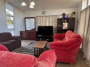 a living room with two red chairs and a television at Holiday at Mount Maunganui in Mount Maunganui