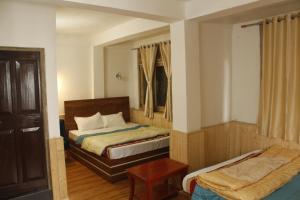 a small bedroom with two beds and a table at Priyatam Stays in Darjeeling +18 photos