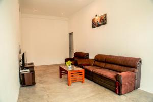 a living room with a brown couch and a table at Painkiller Hiriketiya in Dickwella