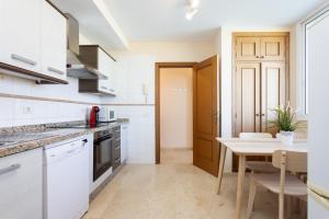 eine Küche mit weißen Schränken, einem Tisch und einem Esszimmer in der Unterkunft El Estanque - Vivienda vacacional in Puerto de la Cruz