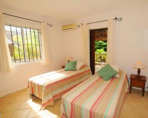 two beds in a room with a window at Ernestville 2 beachfront Villa Pointe aux Canonniers in Pointe aux Cannoniers
