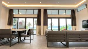 a dining room with a table and chairs and windows at The Vineyard at Tanauan in Tanauan