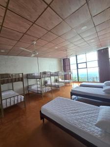 a room with two beds and chairs and windows at Trail Town Lodge in Haputale