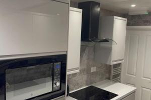 Una cocina con gabinetes blancos y un microondas. en House of Peace & Rest, en Mánchester
