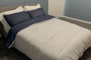 Cama grande con sábanas y almohadas azules y blancas en House of Peace & Rest, en Mánchester