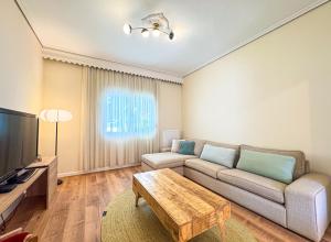 a living room with a couch and a tv at Cityscape Residence with a Patio in Volos