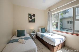 two beds in a room with a window at Coastal Nest in Durban North +24 photos