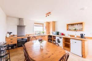 a kitchen with a wooden table with chairs and a stove at The Workshop- Eco Cottage by the Coastal Path in Goodwick
