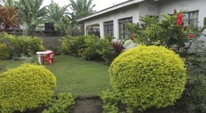 a yard with bushes and a house with a red table at Urafiki House in Arusha