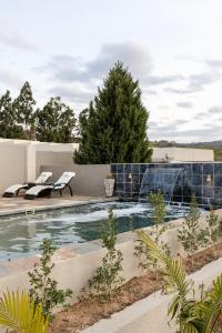 una piscina con 2 sillas junto a una casa en Point R40 Lodge - Conference, Self Catering & Spa, en Nelspruit