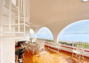 a room with a table and chairs and a balcony at Solemar Sicilia - Ville Paradiso in Santa Flavia