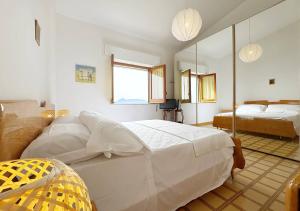 Un dormitorio con una gran cama blanca y un espejo. en Solemar Sicilia - Ville Paradiso, en Santa Flavia