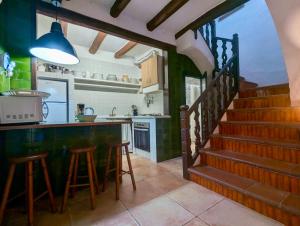 a kitchen with a bar with stools and a staircase at Casa dentro del castillo de Tossa de Mar in Tossa de Mar +16 photos
