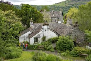 Menschen gehen vor einem alten Haus entlang in der Unterkunft Old Bakers Cottage ground floor apartment centrally located in Grasmere with patio area in Grasmere