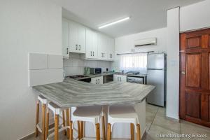 a kitchen with a counter with stools and a refrigerator at 38 Isikhulu in Umdloti +6 photos