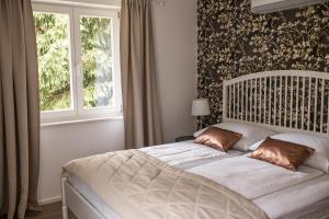 Un dormitorio con una cama blanca con una ventana. en Apartments Villa AnnaMaria, en Bled