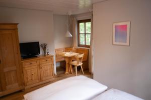 a bedroom with a bed and a table and a television at Lago mio - Pension am See - bei uns verbringt Ihr eine wundervolle Zeit direkt am Wasser in Wörthsee